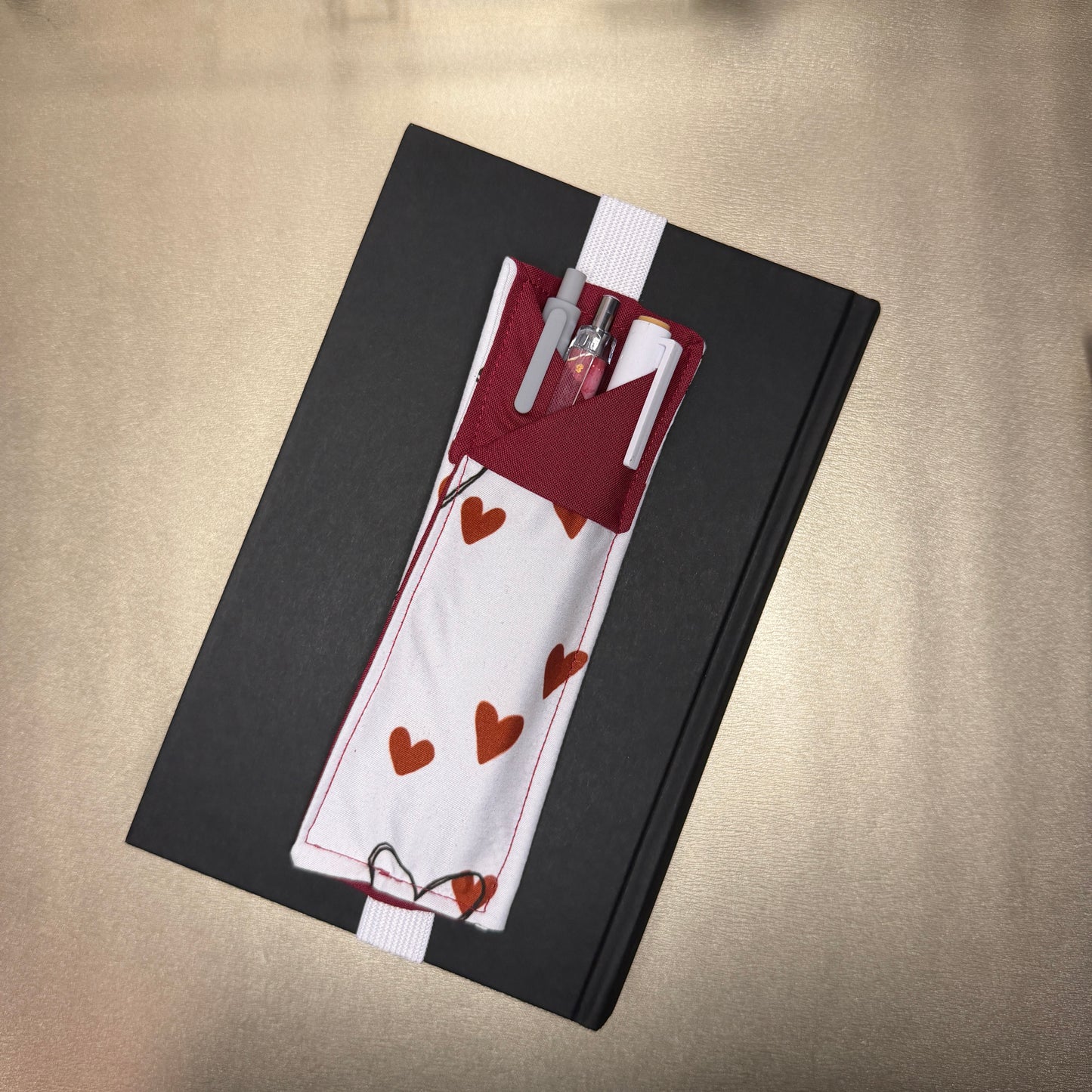 Stifthalter mit Kragen - Herzenmotiv mit Stiften und über ein Buch gespannt als Beispiel