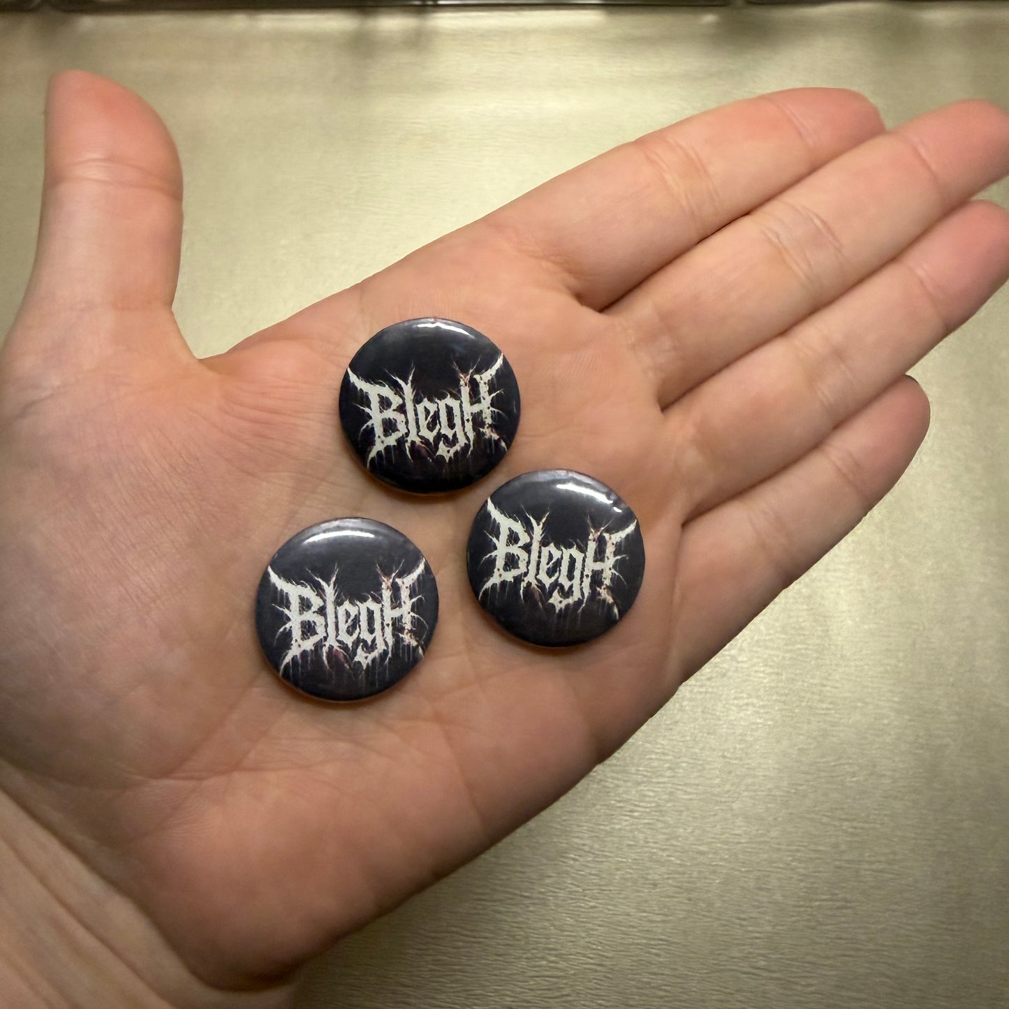 Drei Buttons. Schwarz mit Blegh. 